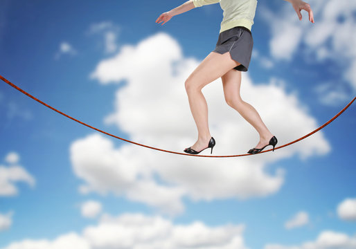 a woman walking on a tightrope made of string for the concept of risk or danger in the business corporate world isolated on a white background