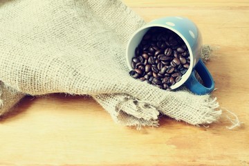 roasted coffee beans in a cup and wood background bags