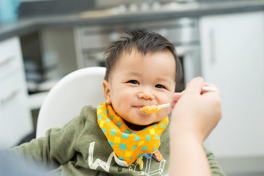 Asian Baby Boy Eating Blend Food On A High Chair