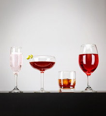 a line of cocktails on a bar studio shot on a gray background with side lights and reflections and space for text