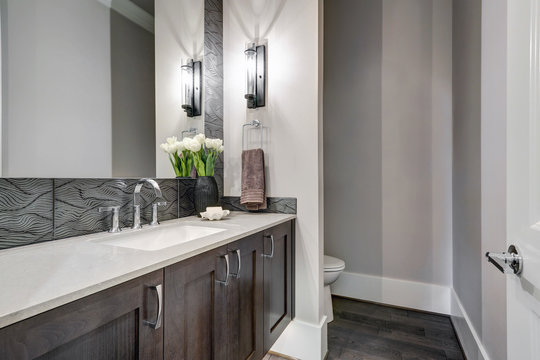 White and brown bathroom boasts a nook filled with taupe vanity