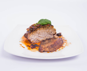 Roast pork decorated with basil on a white plate