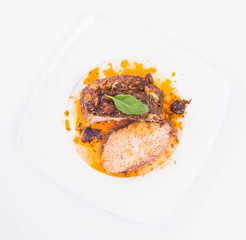 Roast pork decorated with basil on a white plate