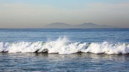 Waves along the beach with islands in the background