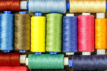 Bobbins with colorful threads on old wooden table background, Sewing background