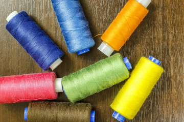 Bobbins with colorful threads on old wooden table background, Sewing background