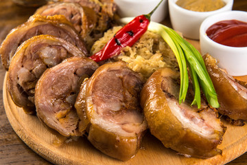 Roasted Pork Roulade with boiled cabbage and sauces on wooden tray. Close up