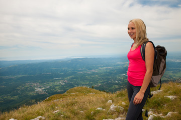 Naklejka na ściany i meble Trekking - woman hiking in mountains on a calm sumer day