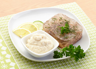 Aspic of beef on white plate with lemon, cucumber, horseradish and parsley