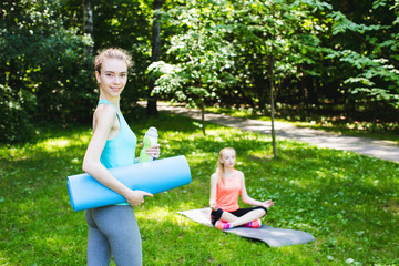 Beautiful woman holding a yoga mat and water bottle.