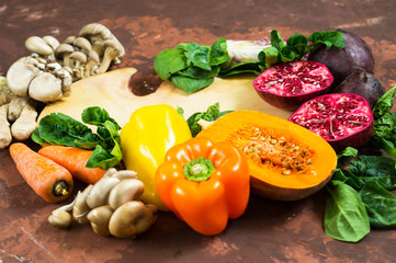 A variety of vegetables, a cutting Board and knife on a brown background