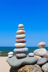 Fototapeta na wymiar high pyramid of stones of different colors on the background of sea and blue sky