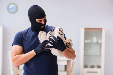 Robber wearing balaclava stealing valuable things