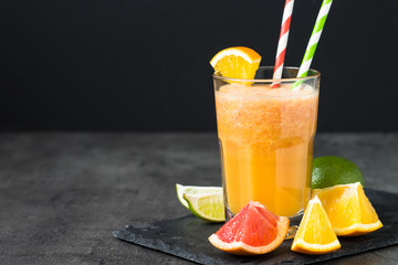 Fresh citrus smoothie juice at dark background.