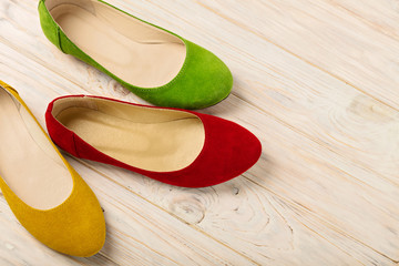 Red, green and yellow women's shoes (ballerinas) on wooden backg