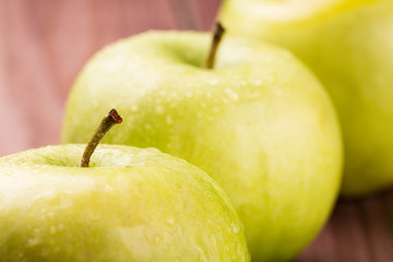 Green apples with stems and water drops close up