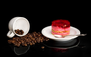 Saucer with cakes and poured coffee beans with mugs on black.