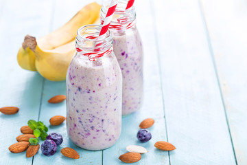 Banana and blueberry diet smoothie with yogurt or milk, almonds and fresh berries in glass bottles, healthy food