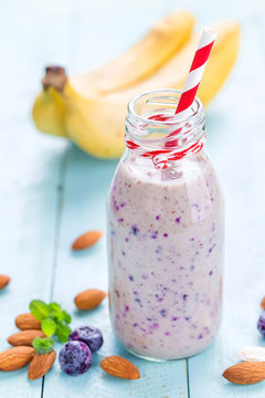 Banana and blueberry diet smoothie with yogurt or milk, almonds and fresh berries in glass bottles, healthy food
