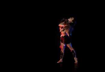 woman athlete in the Amazon costume posing on a black background in the scenic red and blue light.