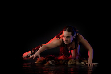 woman athlete in the Amazon costume with fur and skins posing on a black background in the scenic...
