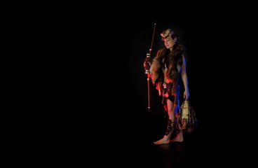 woman athlete in the Amazon costume with fur and skins posing on a black background in the scenic...