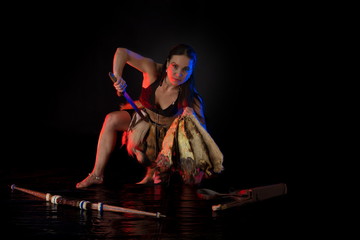 woman athlete in the Amazon costume with fur and skins posing on a black background in the scenic...