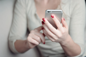 Female hands with red nails holding smart phone