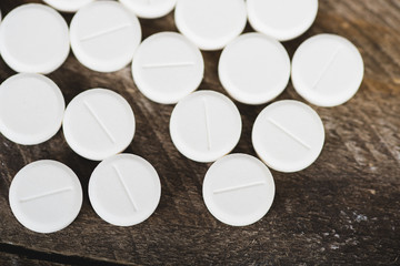 White medicines on wooden background.