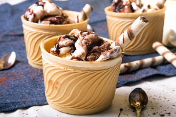 Delicious ice cream in a cup with chocolate sauce and cream rolls