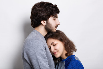Fototapeta premium Young couple in love. A pretty young girl snuggling up to her bearded boyfriend. Sincere love between hipsters. Couple supporting each other and relying on each other having nice time together