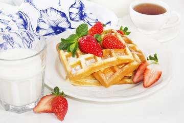 Hot homemade belgian waffles with berries and milk on light back