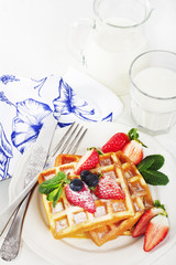 Hot homemade belgian waffles with berries and milk on light back