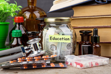 Medical education concept - money glass, books, pharmacy bottles