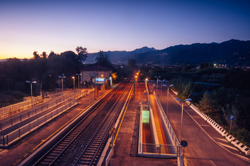 Perspective view of a elevated car road crossing a train track, in the background Apuan Alps, Versilia,Italy