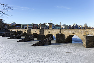 Winter oldest stone Bridge in central Europe above frozen River Otava, Pisek, Czech Republic