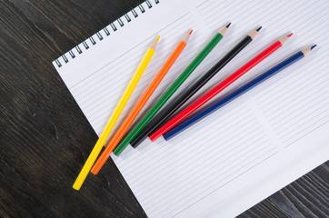 Fototapeta premium Colored pencils and a notebook