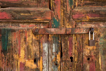 Rustic Wood Door with Padlock and Worn Yellow, Red, White  and Green Paint