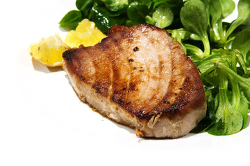 fried tuna steak with corn salad and lemons pieces as a corner background