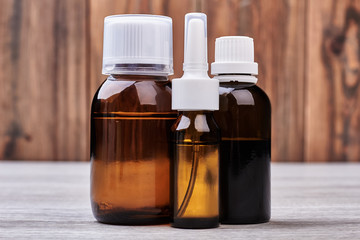 Vials with medicine on wood. Nasal spray and cough syrup.