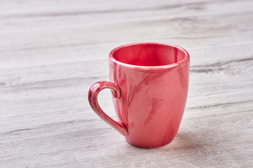 Empty mug on wooden backdrop. Pink ceramic cup.