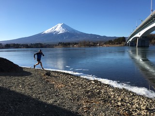 Runner on shoreline of Lake Kawaguchiko with Mount Fuji behind in winter