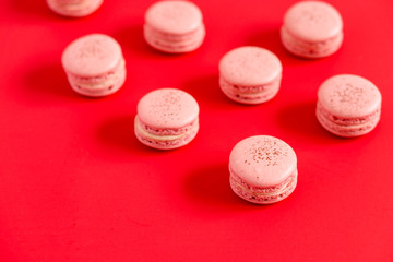 Obraz na płótnie Canvas Macarons on a red background. These romantic french pastries are made of two meringue cookies and a sweet strawberry filling. Light & crisp, these macaroons are the perfect valentine day dessert.