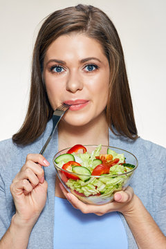 Young smiling woman holding glass bowl with vegetable salad. Isolated portrait.