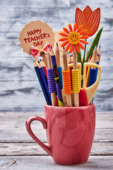 Pencils in a mug. Scissors and decorative flower. Time to celebrate Teacher's Day.