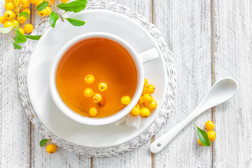 Fresh warmer herbal hawthorn tea with fresh berries in a white cup on wooden background, alternative medicine