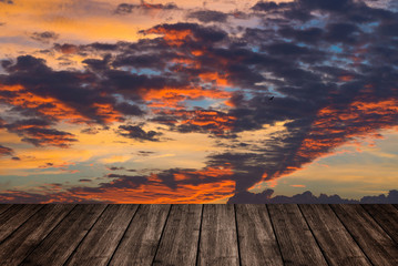 Fototapeta na wymiar Wooden table or terrace on sunset sky and clouds, color and dark