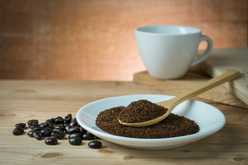 Ground coffee in a white dish resting on a wooden table