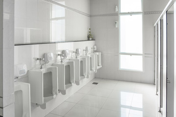 White urinals in clean men public toilet room empty.