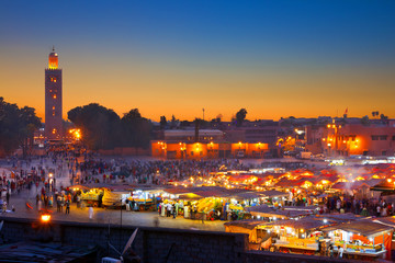 Famous Jemaa el Fna square crowded at dusk. Koutoubia minaret as background. Marrakesh, Morocco